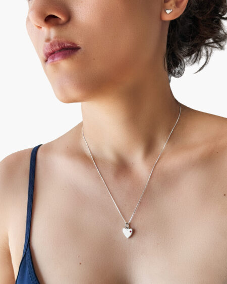 Mujer con collar de corazón hecho a mano en plata 925 con zircón rojo.